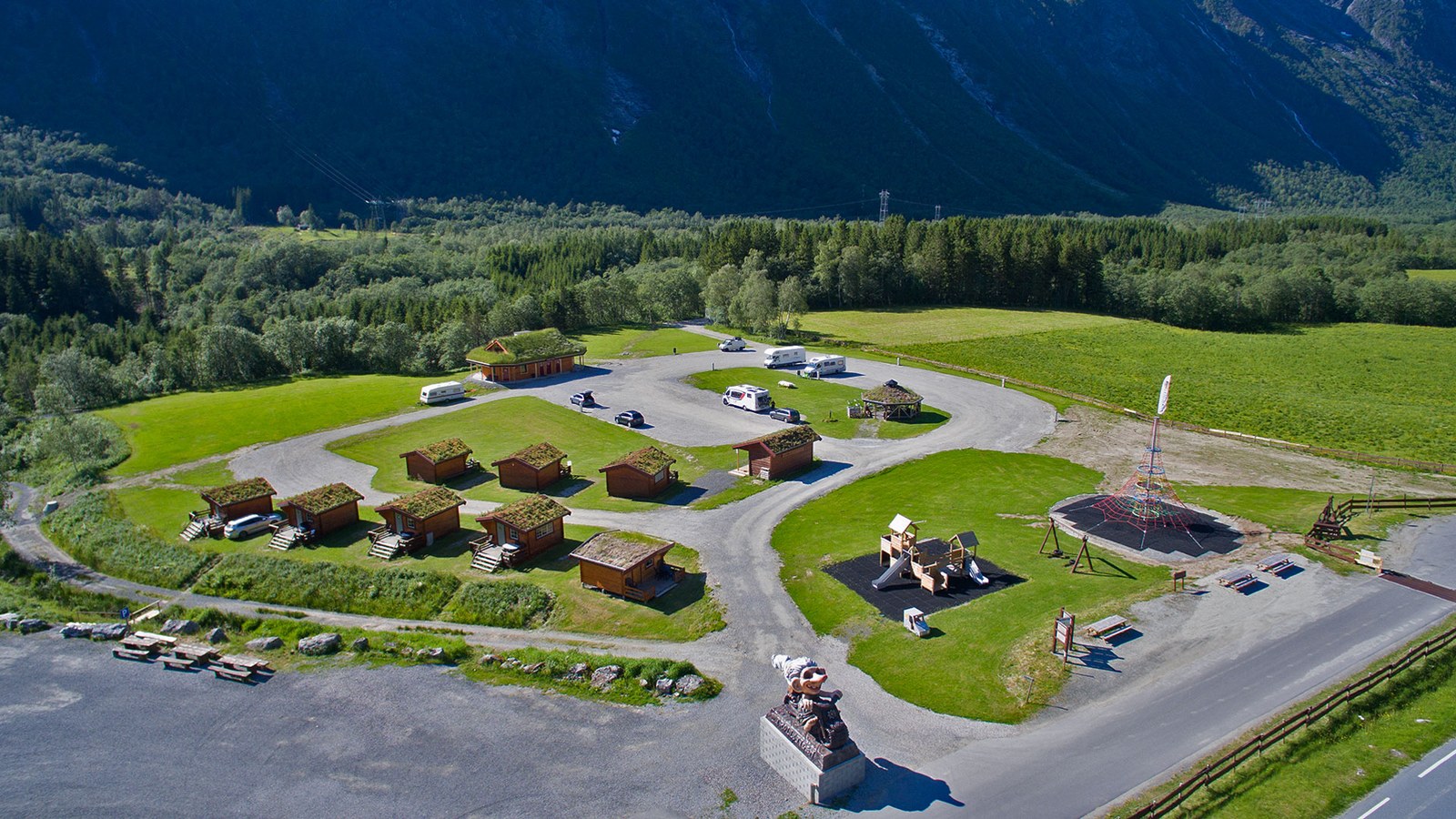 Aerial view of Trollstigen Camping with its grass-roofed cabins and the big troll statue