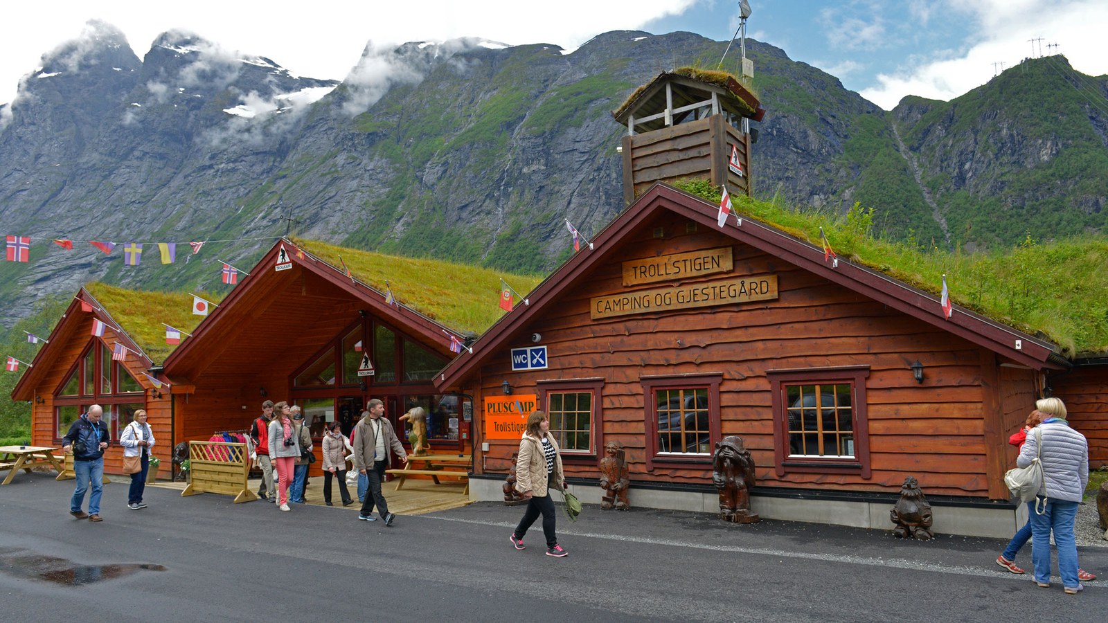 Trollstigen Camping og Gjestegård with sod roofs and troll sculptures, against the Romsdal mountains